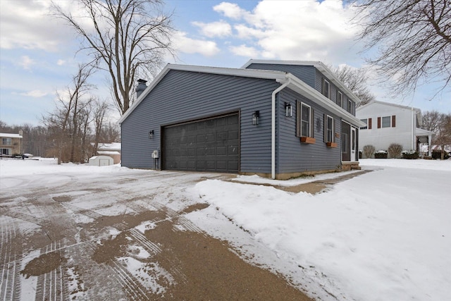 view of snowy exterior featuring a garage