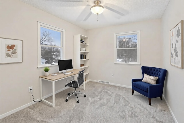 office space with light carpet, ceiling fan, and a textured ceiling