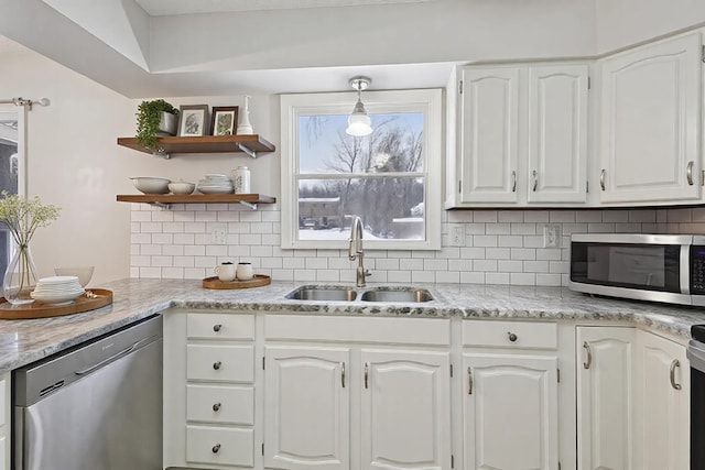 kitchen featuring appliances with stainless steel finishes, hanging light fixtures, white cabinets, backsplash, and sink