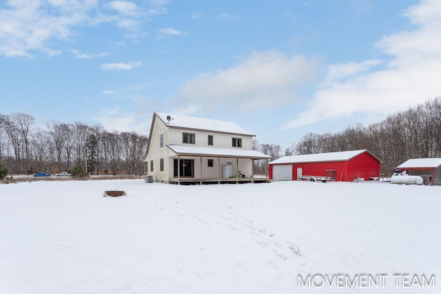 snow covered back of property with a garage and an outdoor structure