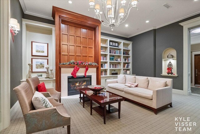 living area featuring built in shelves, crown molding, a chandelier, and light carpet