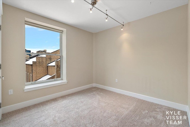 spare room featuring track lighting and carpet