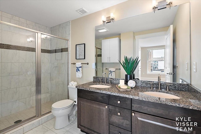 bathroom featuring toilet, a shower with door, and vanity