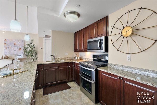 kitchen with light stone countertops, kitchen peninsula, decorative light fixtures, appliances with stainless steel finishes, and sink