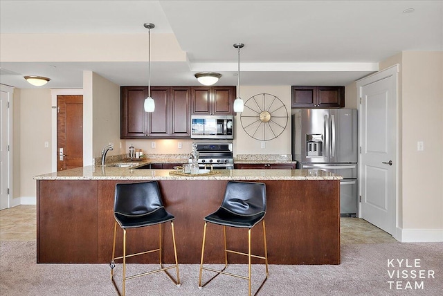 kitchen featuring light stone counters, kitchen peninsula, decorative light fixtures, light colored carpet, and appliances with stainless steel finishes