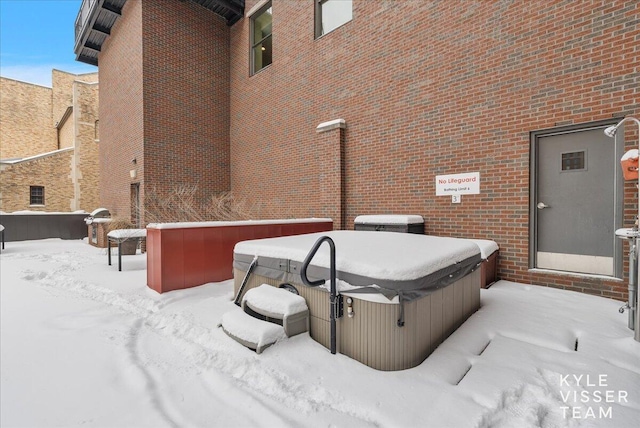 view of snowy exterior with a hot tub