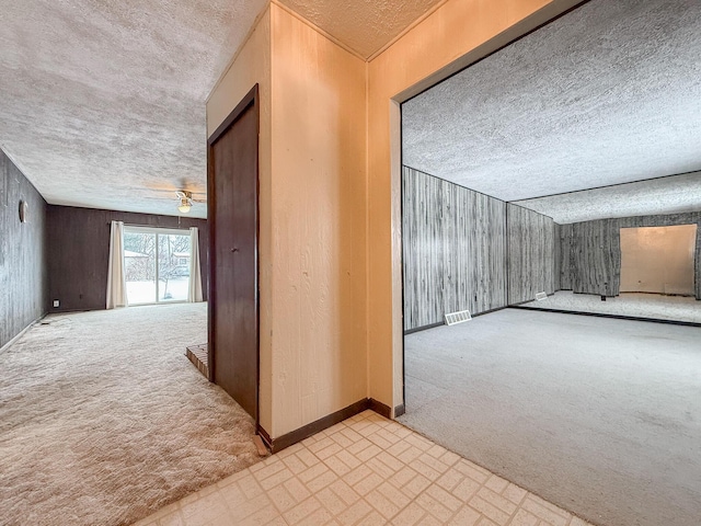 bonus room featuring light colored carpet, ceiling fan, and wood walls