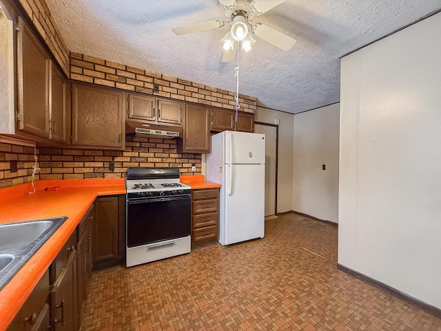 kitchen with white refrigerator, sink, gas range, ceiling fan, and a textured ceiling