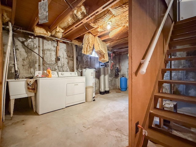 basement featuring washing machine and dryer, electric water heater, and sink