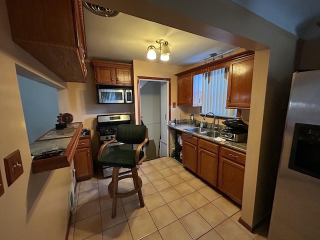 kitchen with sink, light tile patterned flooring, and appliances with stainless steel finishes