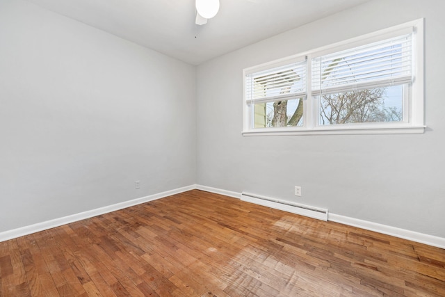 empty room with ceiling fan, a baseboard heating unit, and hardwood / wood-style flooring