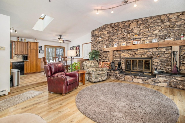 living room featuring vaulted ceiling, light wood-type flooring, ceiling fan, a fireplace, and a textured ceiling