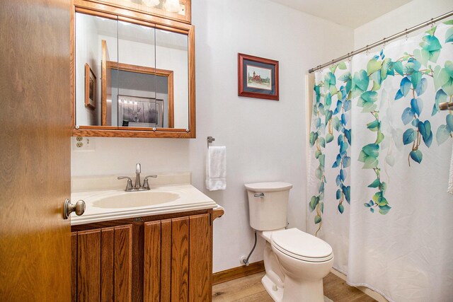 bathroom featuring walk in shower, toilet, vanity, and wood-type flooring