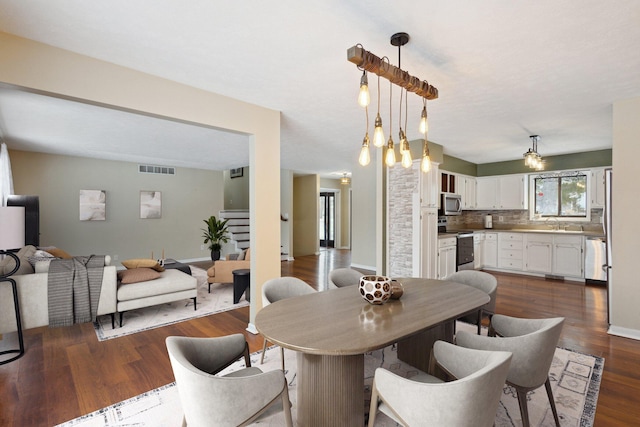 dining space with dark hardwood / wood-style flooring and a chandelier