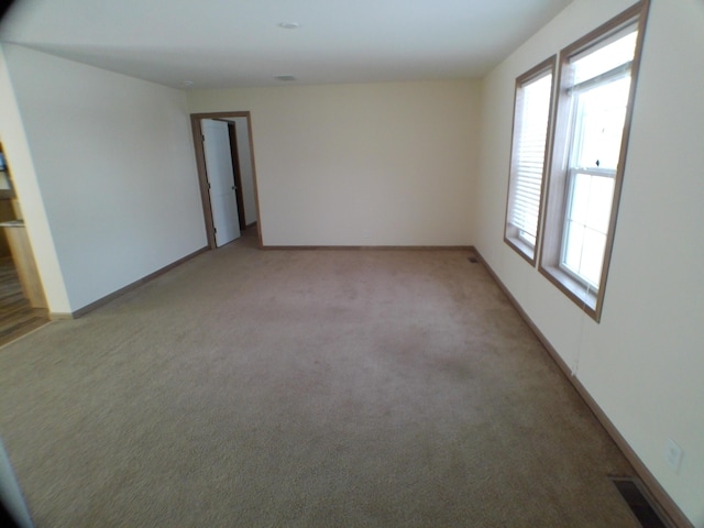 spare room with baseboards, visible vents, and light colored carpet