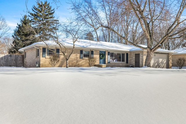 ranch-style home with a garage, brick siding, and fence