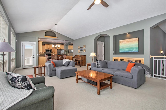 carpeted living room with ceiling fan with notable chandelier and lofted ceiling