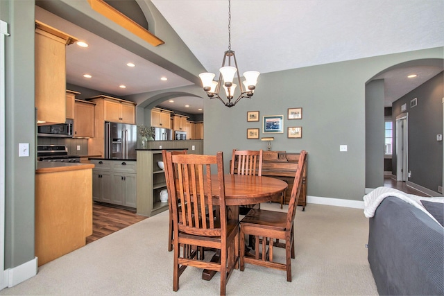 carpeted dining space with an inviting chandelier and lofted ceiling