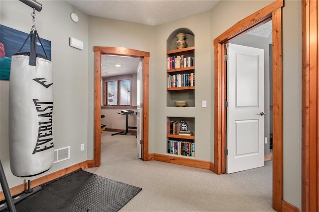 corridor featuring carpet floors, a textured ceiling, and built in features