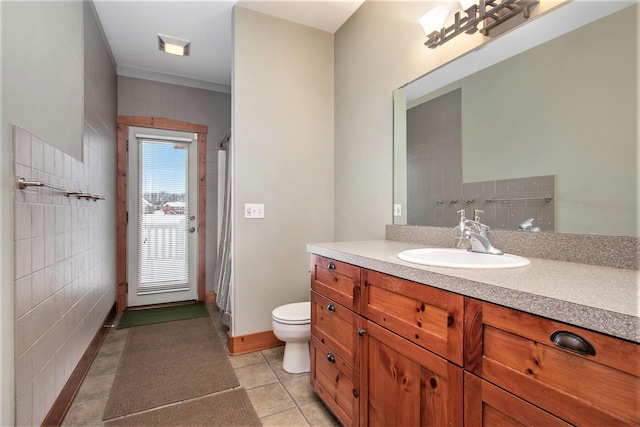 bathroom with toilet, tile patterned flooring, vanity, and tile walls