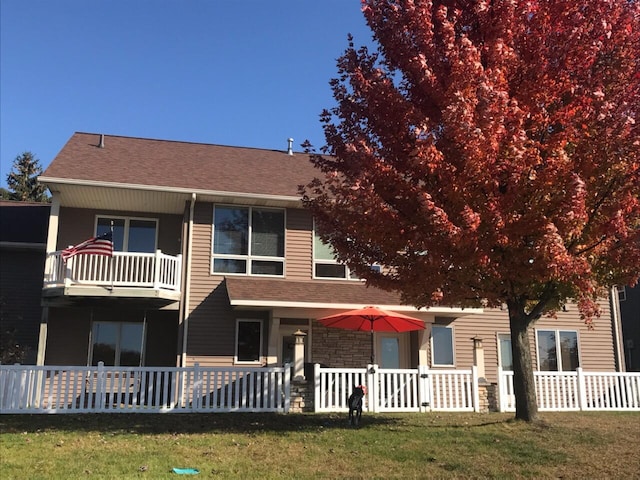 view of front of home featuring a balcony and a front yard