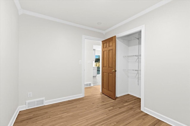 unfurnished bedroom with ornamental molding, a closet, and light hardwood / wood-style flooring