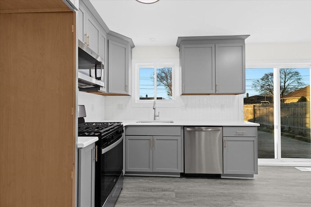 kitchen featuring stainless steel appliances, sink, light hardwood / wood-style floors, and gray cabinets