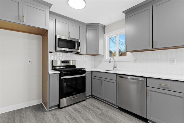 kitchen featuring sink, gray cabinets, stainless steel appliances, and light wood-type flooring