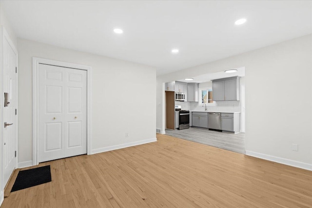 unfurnished living room with sink and light hardwood / wood-style flooring