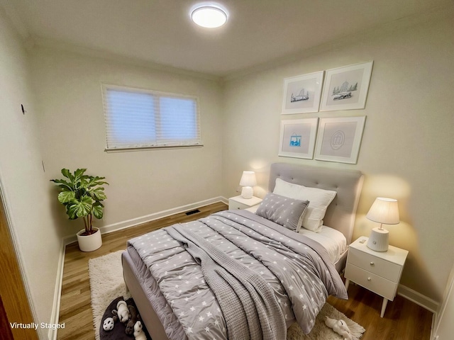 bedroom featuring wood-type flooring and ornamental molding