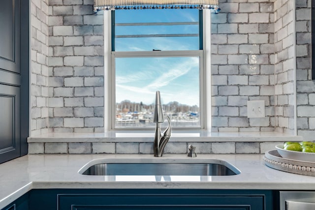 kitchen with blue cabinetry, light stone countertops, and sink