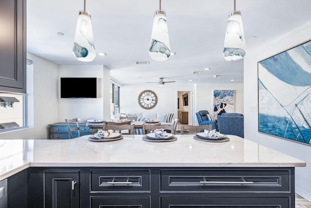 kitchen with light stone counters, ceiling fan, a wealth of natural light, and pendant lighting