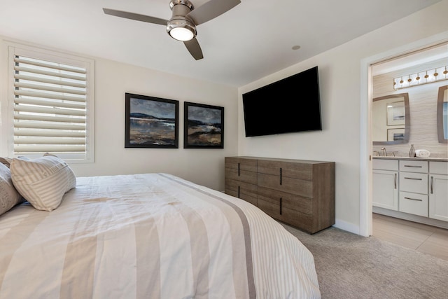 carpeted bedroom featuring sink, ensuite bath, and ceiling fan