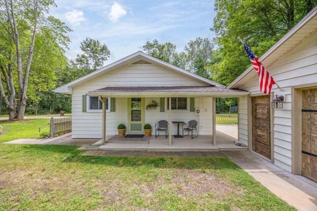 rear view of property with covered porch and a lawn