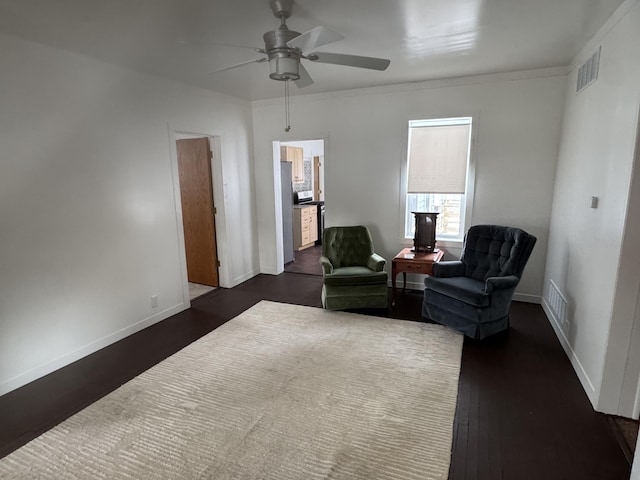 living area featuring dark hardwood / wood-style flooring, crown molding, and ceiling fan