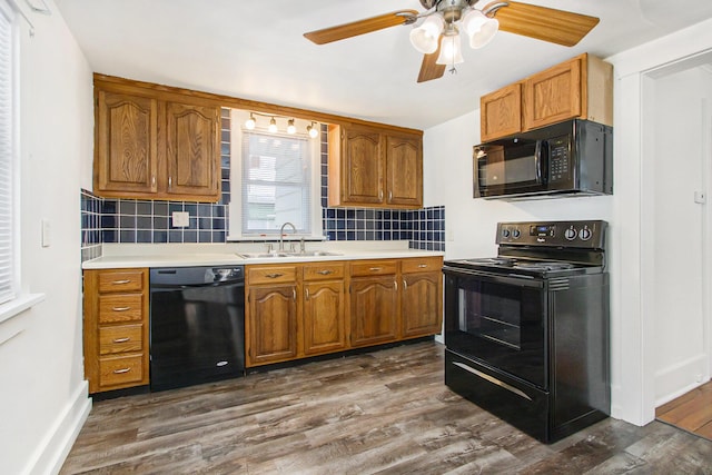 kitchen featuring dark wood-type flooring, decorative backsplash, sink, and black appliances