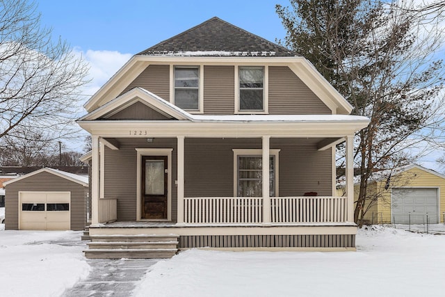 view of front of property with a shingled roof, a detached garage, a porch, and an outdoor structure