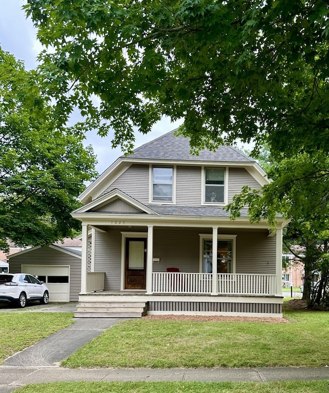 view of front facade with a porch, roof with shingles, and a front lawn