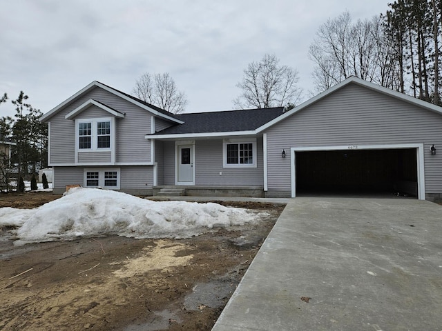 split level home with a garage, driveway, and roof with shingles