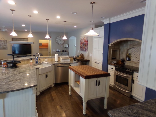 kitchen featuring decorative light fixtures, a spacious island, white cabinetry, dark stone counters, and appliances with stainless steel finishes