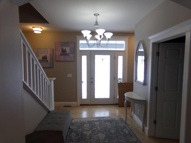 tiled foyer with a notable chandelier