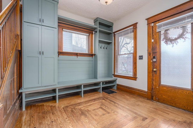 mudroom featuring a wealth of natural light, light parquet floors, and a textured ceiling