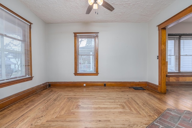 empty room featuring ceiling fan, light parquet floors, and a textured ceiling