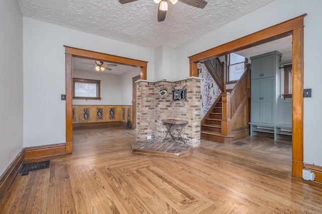 unfurnished living room with a textured ceiling and ceiling fan