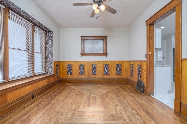 unfurnished room featuring ceiling fan, wood walls, and light parquet floors