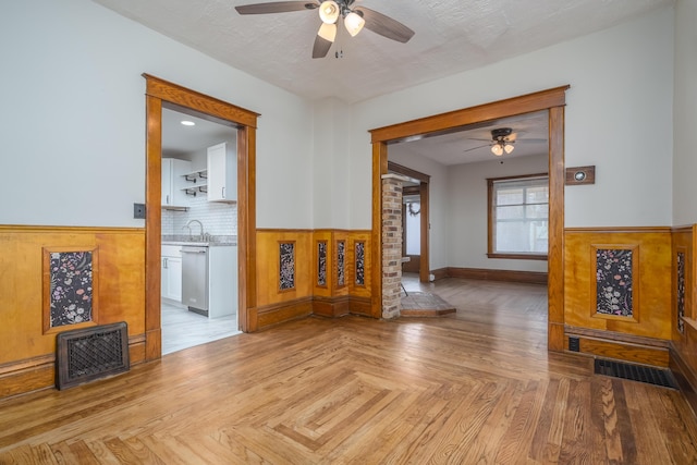 living room with a textured ceiling, ceiling fan, sink, and light parquet flooring