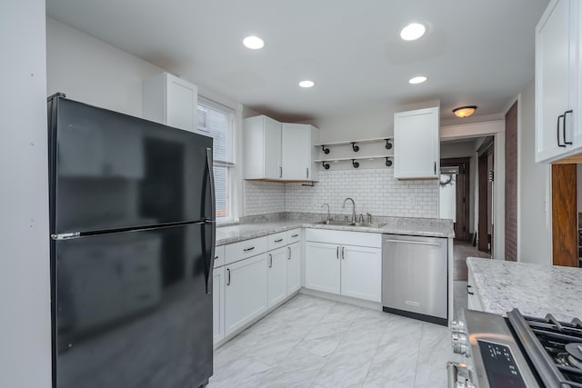 kitchen with light stone counters, stainless steel appliances, white cabinetry, and sink