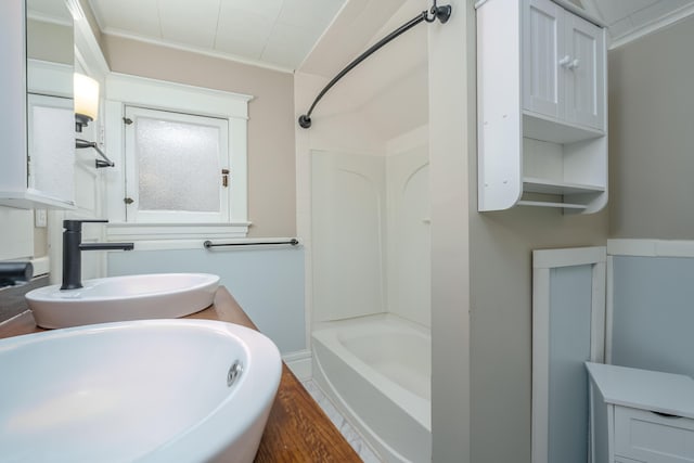 bathroom featuring shower / washtub combination, sink, and ornamental molding