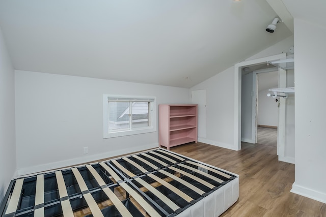 unfurnished bedroom with light hardwood / wood-style floors and lofted ceiling