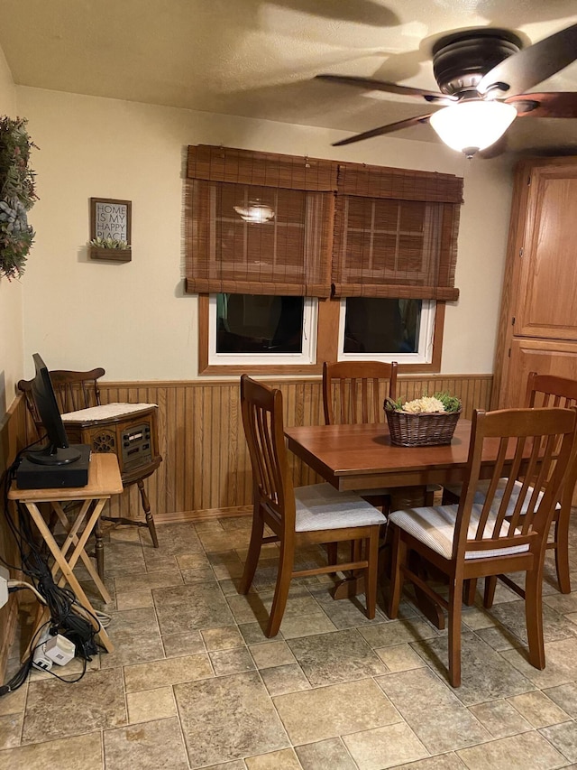 dining area with wood walls and ceiling fan